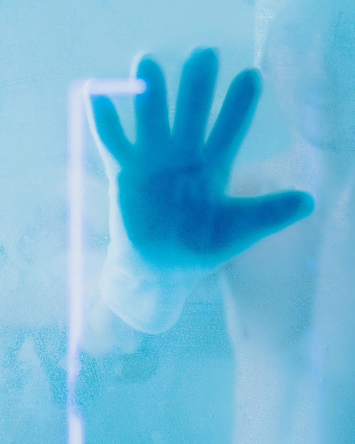 A hand against the frosted glass of the Freezlab cryotherapy chamber